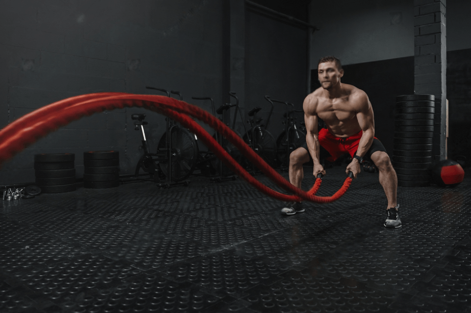 Man wear red shorts doing battle ropes exercise at the crossfit gym. The motivation sport concept. Copy space