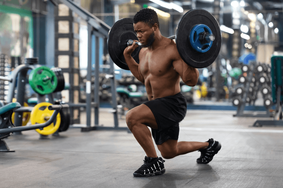 Shirtless black guy sportsman making squats with barbell in modern gym copy space. Handsome african american young muscular man working out with weights building up muscles